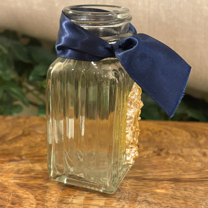 Gilded Cross Adorning the Glass Vessel with Navy Ribbon Acent