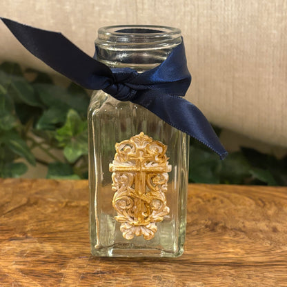 Gilded Cross Adorning the Glass Vessel with Navy Ribbon Acent